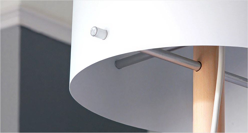 Close-up of the AmbientLight lamp: a white shade with a small LED module, on a wooden pole