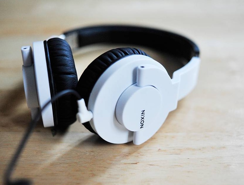 White Nixon Stylus headphones resting on a wooden table